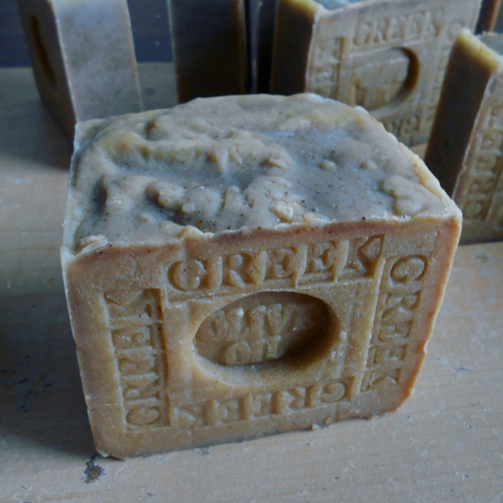 A handmade bar of Greek Olive Oil soap in a olive  color, embossed with the brand name 'GREEK OIL' and a central oval logo. 