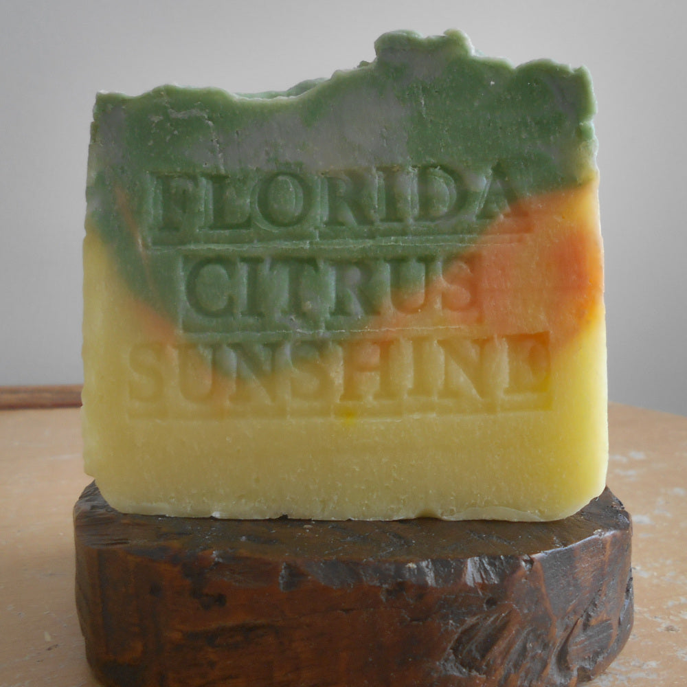 Green and orange soap bars with 'Florida Citrus Sunshine' text on a wooden surface.