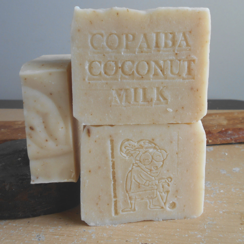 Two bars of soap with 'Copaiba Coconut Milk' text on a wooden surface.