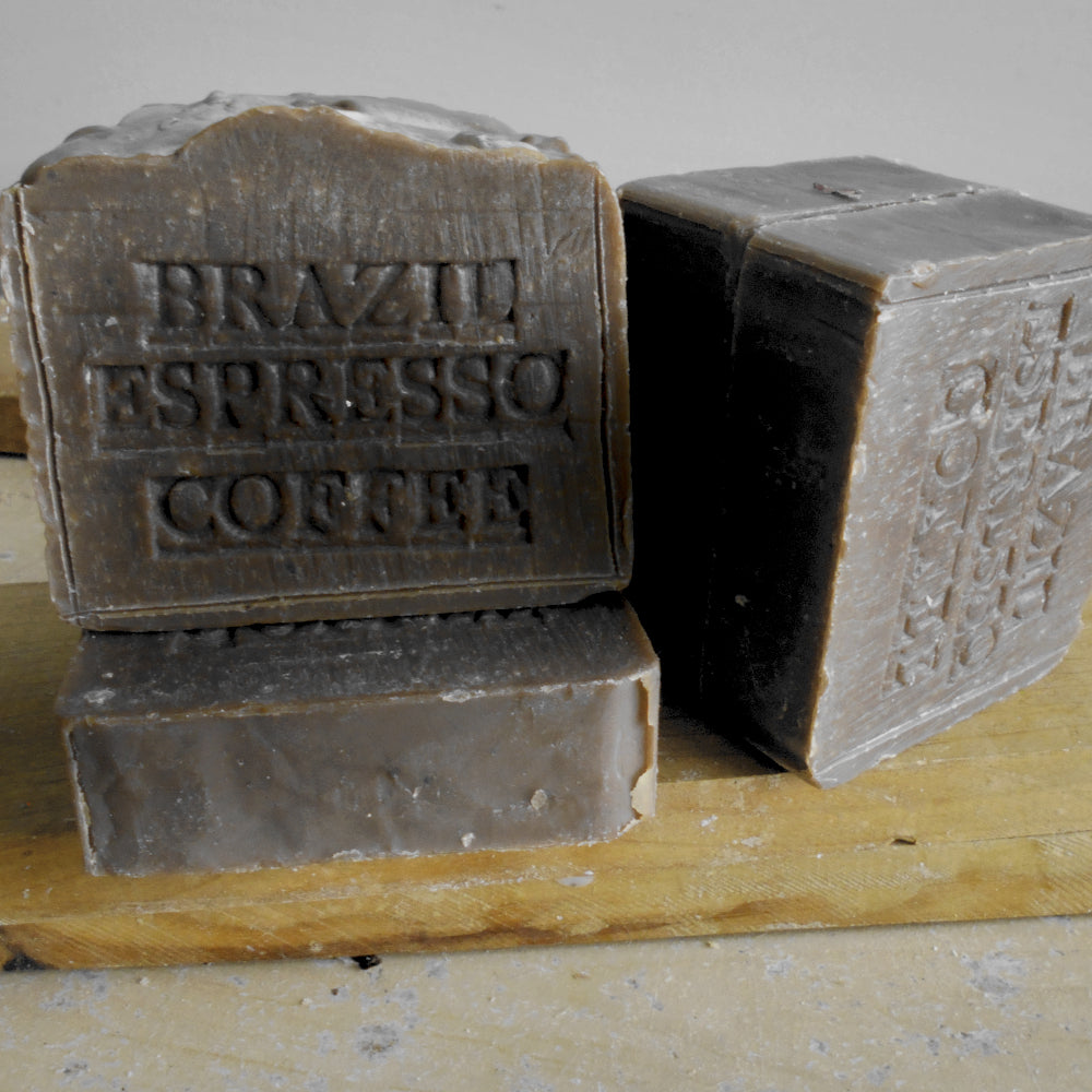 Three blocks of coffee-scented soap labeled 'Brazil Espresso Coffee' on a wooden surface.