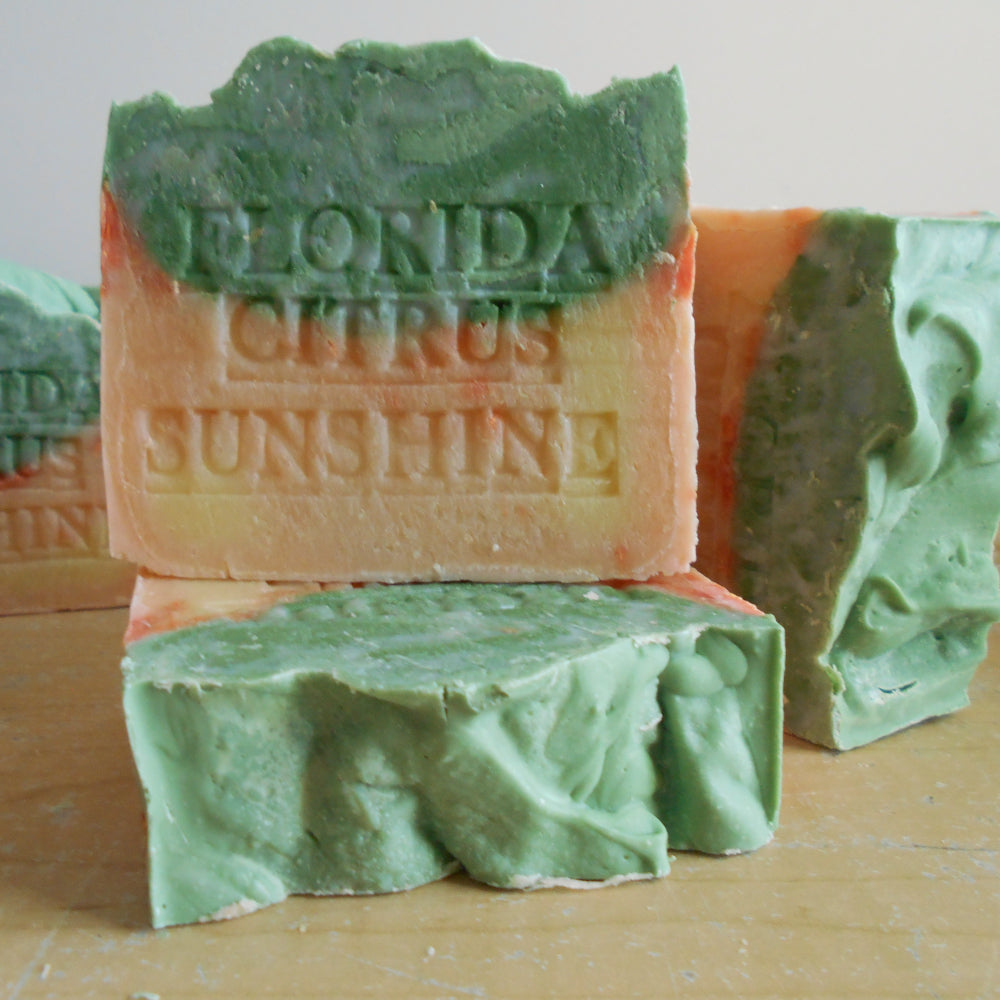 Green and orange soap bars with 'Florida Citrus Sunshine' text on a wooden surface.