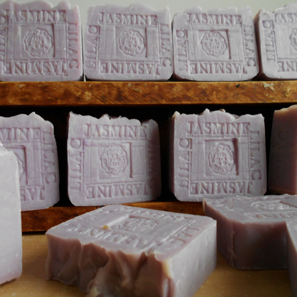 Rows of soap bars with 'Jasmine' Lilac branding on a wooden shelf.