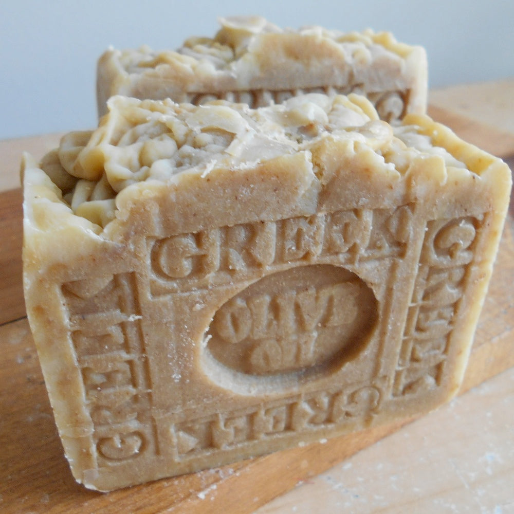 Block of olive oil soap with 'Green & Black's' branding on a wooden surface.