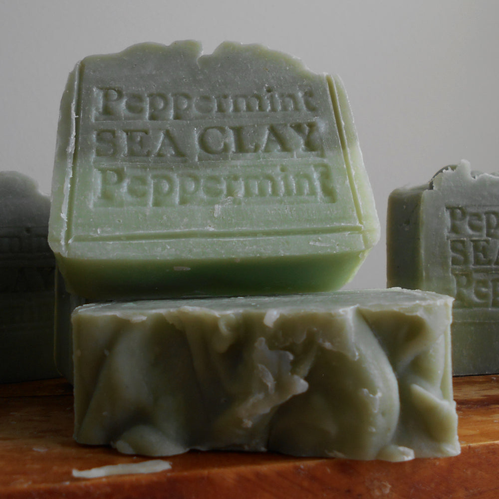 Green soap bars with 'Peppermint Sea Clay' text on a wooden surface.