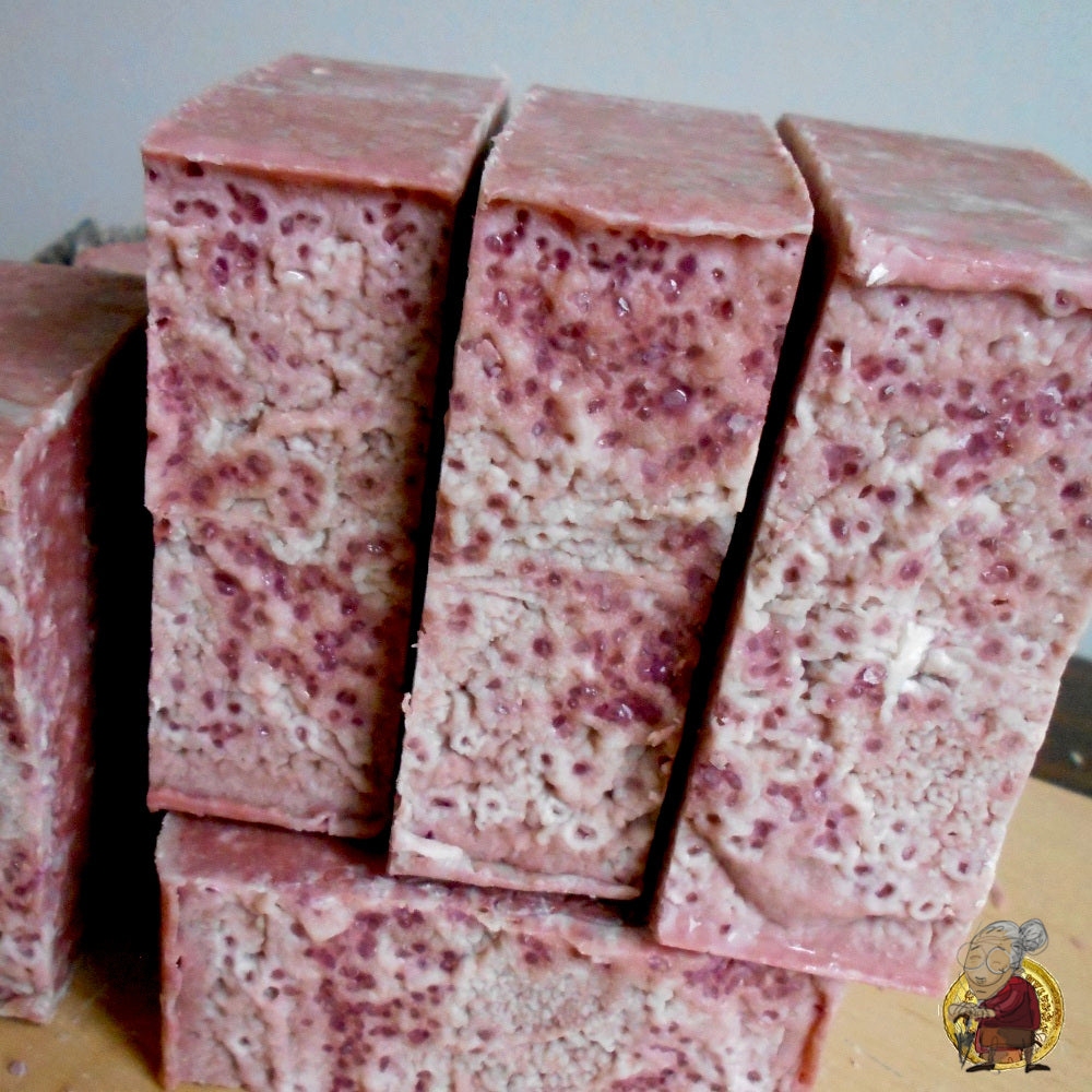 Rosehip natural soap The soap bars have a natural, rustic appearance, with some texture on the surface, and are displayed on a wooden stand.