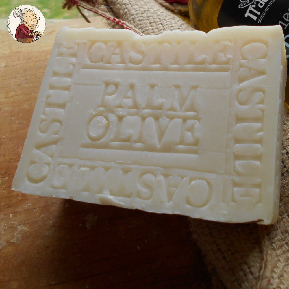 A rectangular white-cream color soap bar with embossed text reading "Castile Olive Palm" .  rustic appearance. An logo the  top   side.